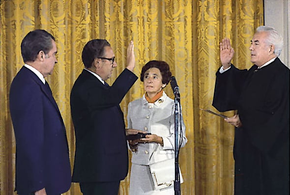 Kissinger being sworn in as Secretary of State by Chief Justice Warren Burger, September 22, 1973. Kissinger's mother, Paula, holds the Bible as President Nixon looks on.