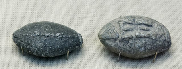 Ancient Greek lead sling bullets with a winged thunderbolt molded on one side and the inscription "ΔΕΞΑΙ" ("take that" or "catch") on the other side