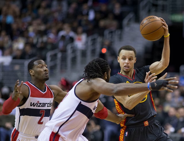 Curry about to pass while being guarded by John Wall and Nenê of the Washington Wizards. Curry averaged 7.7 assists per game during the 2014–15 NBA regular season, good enough for sixth best in the league.