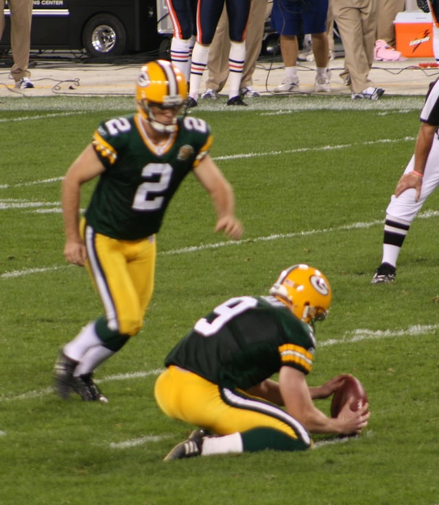 Green Bay Packers placekicker Mason Crosby attempts a field goal by kicking the ball from the hands of a holder. This is the standard method to score field goals or extra points.