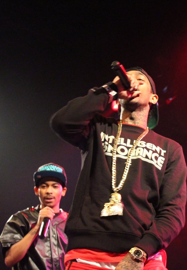 Hussle (front) performing with singer TeeFlii in December 2013.