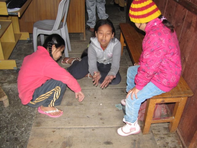 Nepali children playing a variant of knucklebones with pebbles.