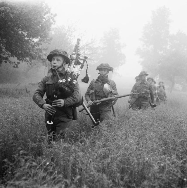 Led by their piper, men of the 7th Battalion, Seaforth Highlanders (part of the 46th (Highland) Brigade), advance during Operation Epsom on 26 June 1944