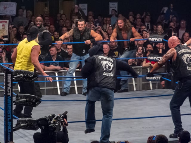 Aces & Eights (Devon, Garrett Bischoff, and Wes Brisco on the far side of the ring, with "VP" - later revealed to be D'Lo Brown - and D.O.C. on the near side) surround General Manager Hulk Hogan on the February 14, 2013, episode of Impact