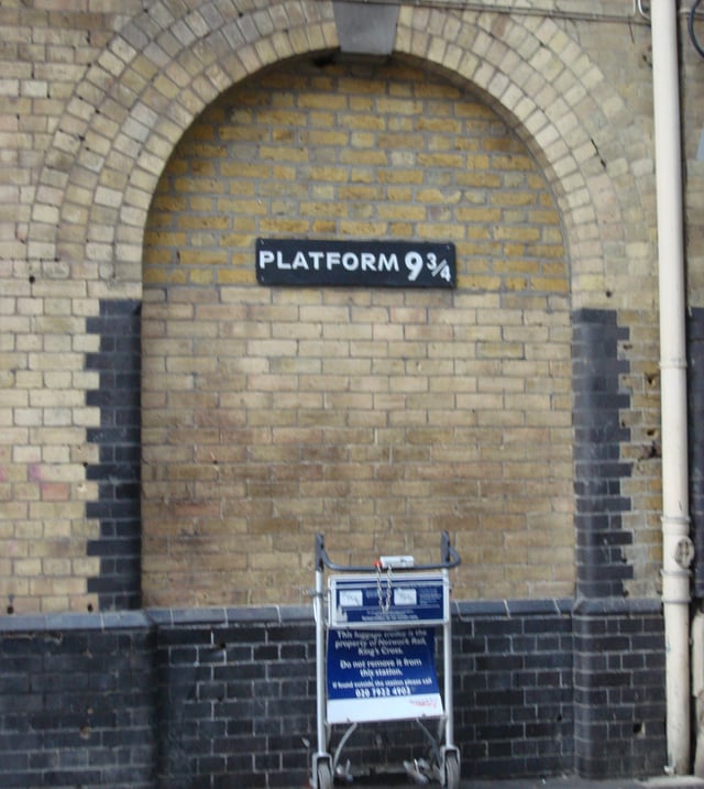 Imitation of the fictional Platform ​9 3⁄4 at the real King's Cross railway station, with a luggage trolley apparently halfway through the magical wall