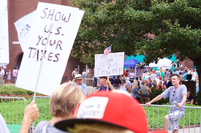 A protester holding a sign toward Trump supporters asking for Trump to publicly release his tax returns, at an August 9, 2016, campaign event in Wilmington, North Carolina