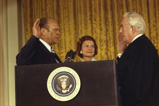 Gerald Ford is sworn in as the 38th President of the United States by Chief Justice Warren Burger in the White House East Room, while Betty Ford looks on.