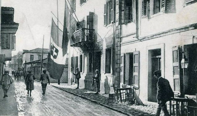 The flag of Italy is shown hanging alongside an Albanian flag from the balcony of the Italian prefecture in Vlorë, Albania during World War I.