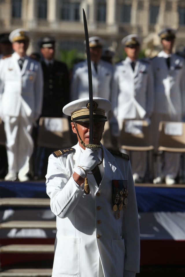 A captain of the French Navy salutes by holding the flat of his saber to his face during the ceremonies of the 14th of July in Toulon.