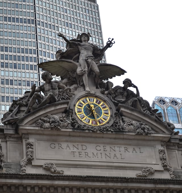 Glory of Commerce, a sculptural group featuring Hercules, Minerva, and Mercury, sits atop Grand Central Terminal in Midtown Manhattan, New York City, one of the ten busiest tourist attractions in the world. In the middle of the grouping is the 13-foot (4.0 m) clock, the world's largest example of Tiffany glass.