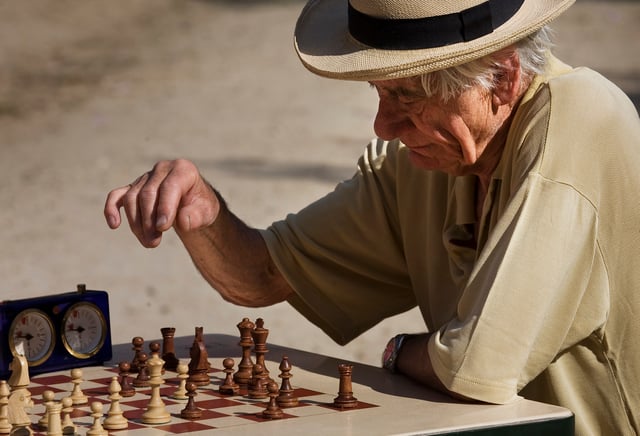 An older adult human male European in Paris – playing chess at the Jardin du Luxembourg.