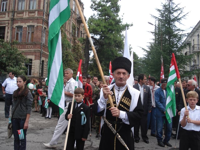 Abkhazians carrying the republic's flags in a parade.