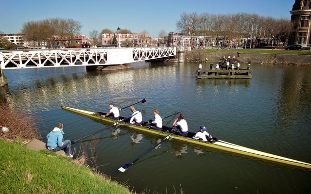 Triton rowing club team pauses with their coach by the Muntbrug, a rotating bridge built in 1887.