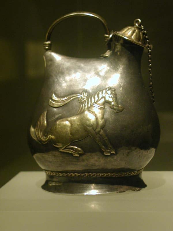 A Tang period gilt-silver jar, shaped in the style of northern nomad's leather bag decorated with a horse dancing with a cup of wine in its mouth, as the horses of Emperor Xuanzong were trained to do.