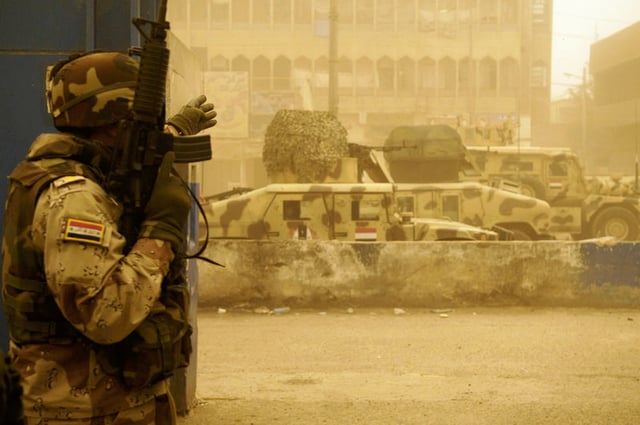 An Iraqi soldier and vehicles from the 42nd Brigade, 11th Iraqi Army Division during a firefight with armed militiamen in the Sadr City district of Baghdad 17 April 2008