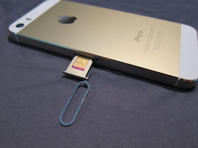 An iPhone 5S with the SIM slot open.