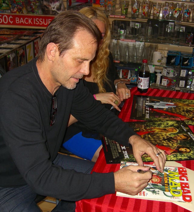 Actor Michael Biehn autographing a copy of Mad #268 (January 1987) which parodies one of Biehn's films, Aliens