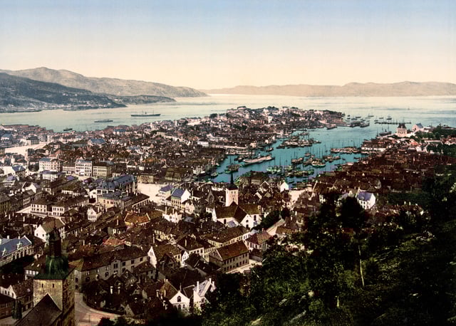 An historic photochrom of Bergen near the end of the 19th century. Visible are Bergen Cathedral (Domkirken) in the bottom left corner, Holy Cross Church in the middle, the bay (Vågen) with its many boats and the Bergenhus Fortress to the right of the opening of Vågen.