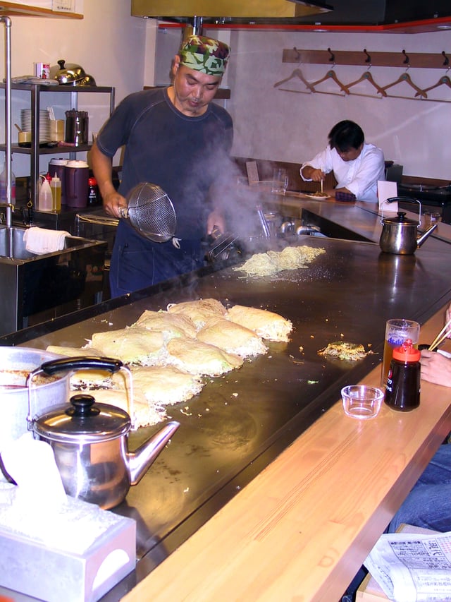 A man making an okonomiyaki at a restaurant in Hiroshima