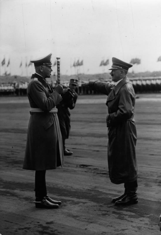 Werner von Blomberg (left) saluting Adolf Hitler (right) with a baton at the 1937 Nuremberg Rally.