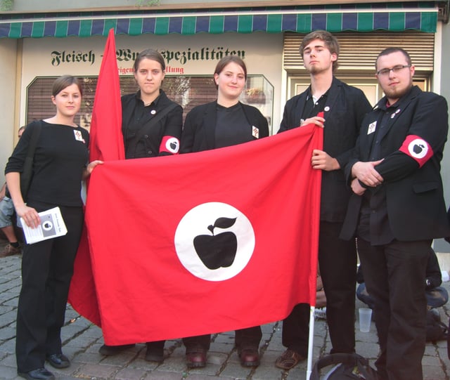 Apple Front activists in typical uniform with satirized right extremist symbols and bearing