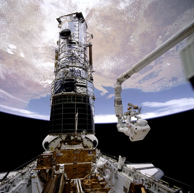 Story Musgrave attached to the RMS servicing the Hubble Space Telescope during STS-61