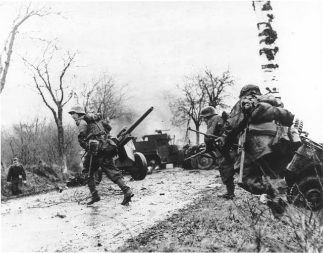 German troops advancing past abandoned American equipment