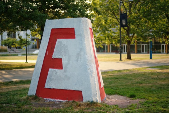 The UBC Engineering Cairn, a chamfered tetrahedral concrete block with a large red "E" on each of its three sides, shown here in its unvandalized state. Painting the cairn is a favourite hobby of student clubs and rival faculties.