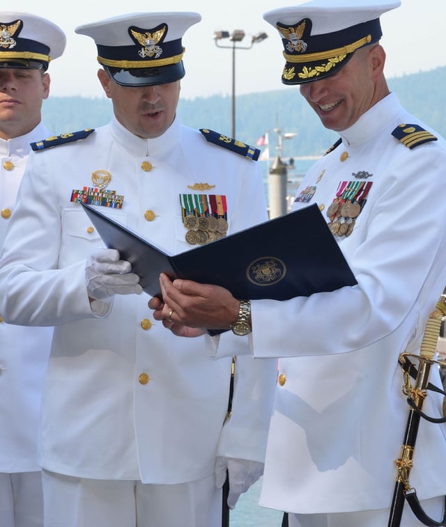 A Coast Guard chief warrant officer (CWO2, left) and an officer (commander, O-5, right) wearing Full Dress Whites.