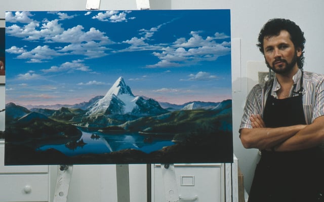 Artist Dario Campanile poses with a picture Paramount commissioned him to paint for its 75th anniversary in 1987. The company later used the painting as a basis for its new logo. That logo was introduced as a prototype in the 1986 film The Golden Child; the 1987 film Critical Condition was the first to feature the finalized version of the logo. 1999's South Park: Bigger, Longer & Uncut was the first to use an enhanced version of the logo, which was last used on 2002's Crossroads.