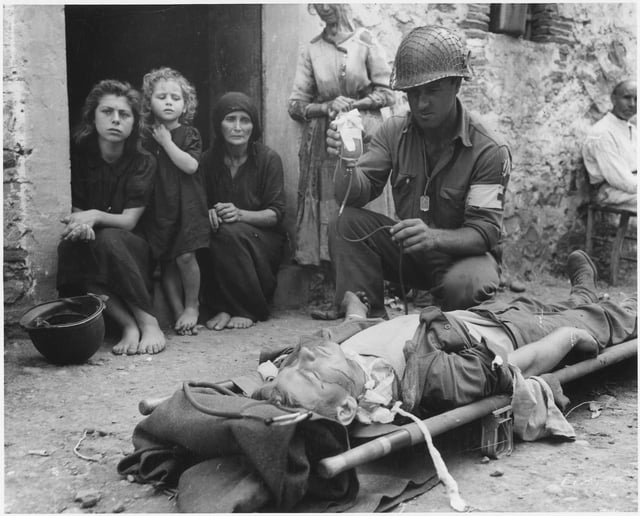 Wounded American soldier receiving blood plasma, Sicily, 9 August 1943.
