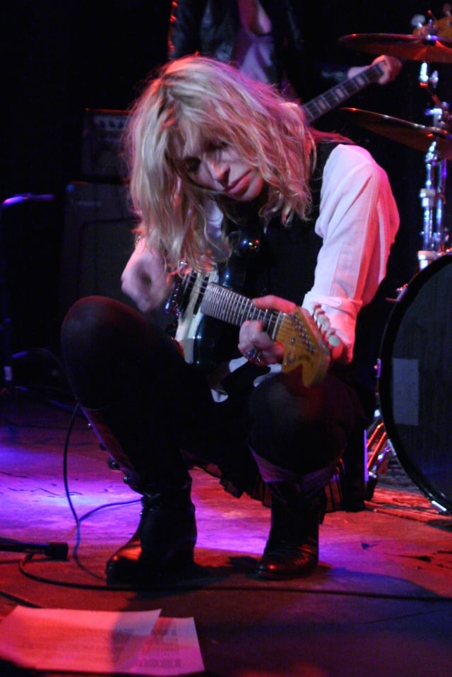 Love, pictured playing a Fender Mustang in 2012, has often played both Fender and Rickenbacker guitars throughout her career