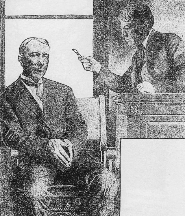 Judge Kenesaw Mountain Landis wags his pen at John D. Rockefeller, who is sitting in the witness stand, during the Standard Oil case on July 6, 1907