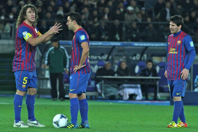 Xavi (middle) with Barcelona teammates Carles Puyol (left) and Lionel Messi (right) in December 2011
