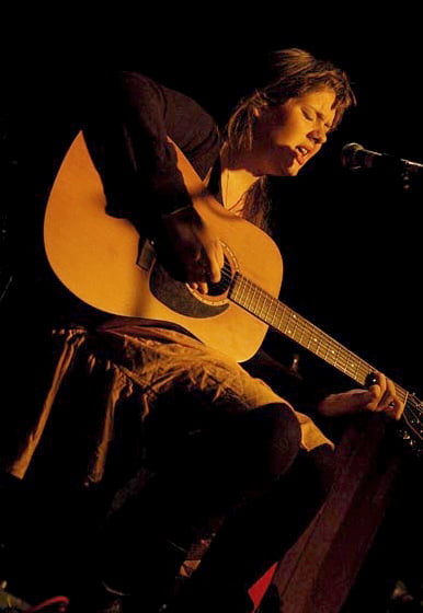 Teenaged Adele performing on an acoustic guitar in Kilburn, London, in 2007