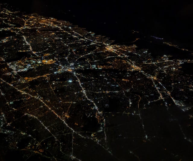 Nighttime aerial view of much of Nassau County, from the west-northwest; Hempstead is in the center, with roads projecting out in various directions; bridges to Jones Beach Island are at the upper right.  The Grand Central Parkway–Cross Island Parkway interchange, barely visible at the lower left, is just outside the county, within Queens.