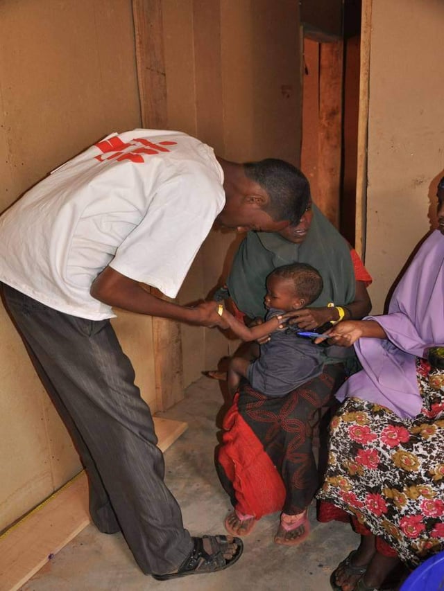 An MSF health worker examines a malnourished child in Ethiopia, July 2011