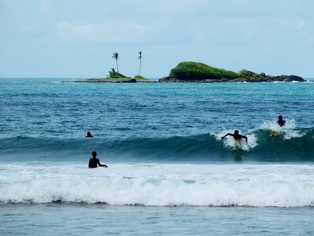 Surfers surfing and big wave surfing at Busua Beach in Western region