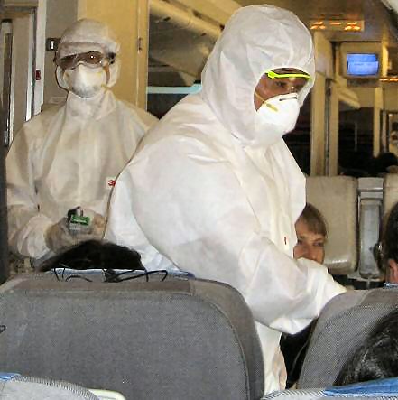 Chinese inspectors on an airplane, checking passengers for fevers, a common symptom of swine flu