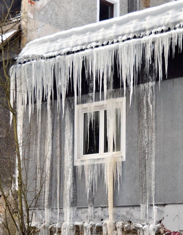 Icings resulting from meltwater at the bottom of the snow pack on the roof, flowing and refreezing at the eave as icicles and from leaking into the wall via an ice dam.