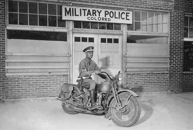 An African-American Military Policeman on a motorcycle in front of the "colored" MP entrance during World War II.