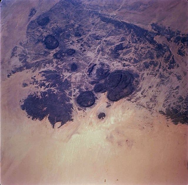 Circular granite massifs (dark areas). A volcanic crater can be seen at the lower left. NASA image approximately 130 km (81 mi) across.