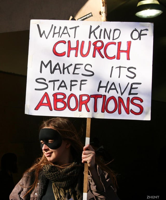 Protester against Scientology, holding a sign which reads: "What kind of church makes its staff have abortions"