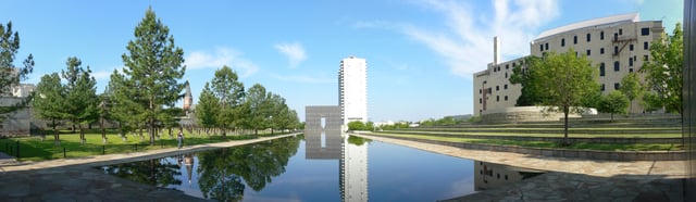 Panoramic view of the memorial, as seen from the base of the reflecting pool. From left to right are the memorial chairs, Gate of Time and Reflecting Pool, the Survivor Tree, and the Journal Record Building.