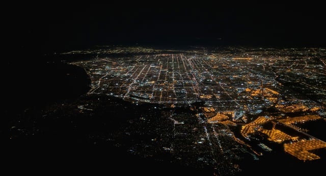 In this night-time aerial photograph of Los Angeles, San Pedro is in the center and right foreground, including part of the brightly lit Terminal Island. The dark peninsula to the left of San Pedro is Palos Verdes.