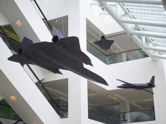 Suspended from the ceiling of the glass-enclosed atrium: three models of the U-2, Lockheed A-12, and D-21 drone. These models are exact replicas at one-sixth scale of the real planes. All three had photographic capabilities. The U-2 was one of the first espionage planes developed by the CIA. The A-12 set unheralded flight records. The D-21 drone was one of the first crewless aircraft ever built. Lockheed Martin Corporation donated all three models to the CIA.