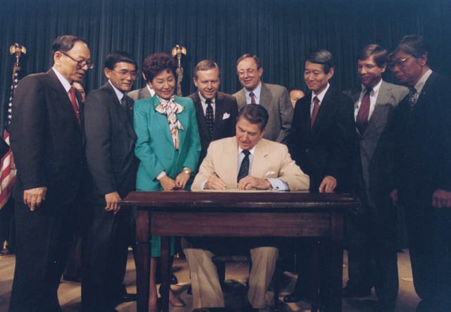 President Reagan signing the Civil Liberties Act with Wilson looking on