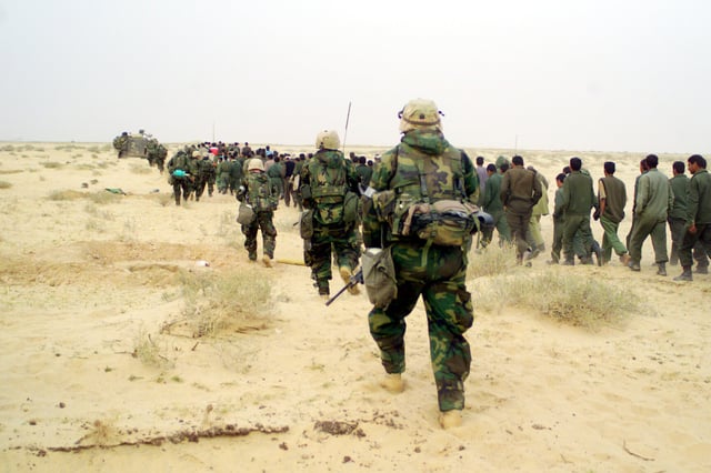 US Marines escort captured enemy prisoners to a holding area in the desert of Iraq on 21 March 2003.