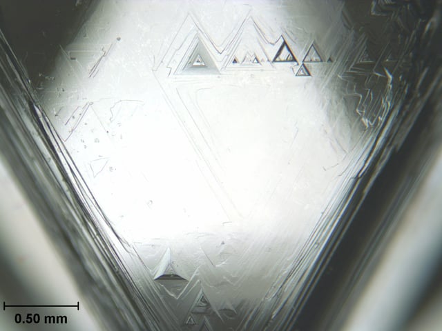 One face of an uncut octahedral diamond, showing trigons (of positive and negative relief) formed by natural chemical etching