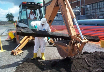 A member of the Radiation Safety Support Team, wearing a hazmat suit, tests excavated soil.